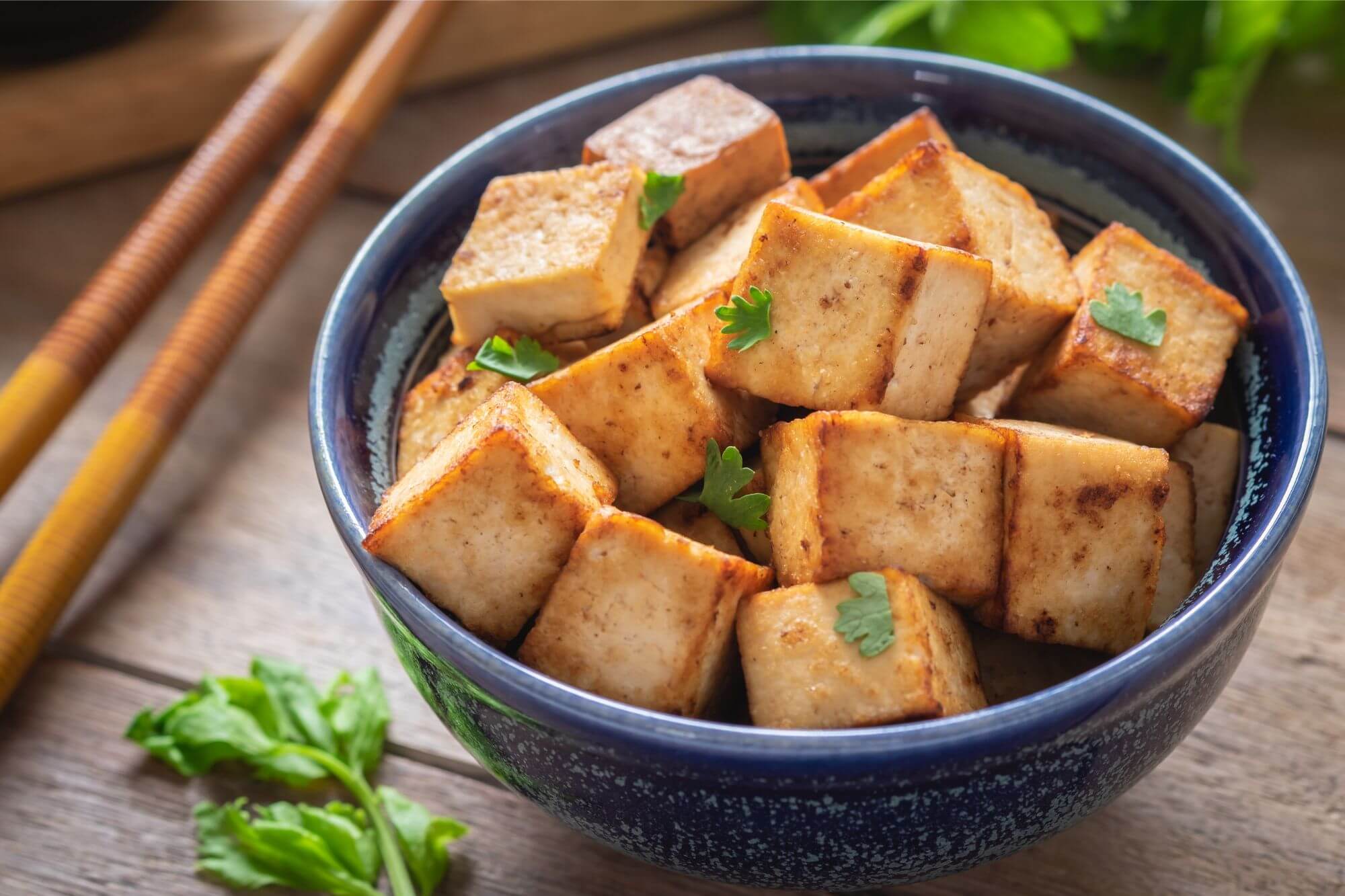 Tofu in a bowl with chopsticks on a wooden table